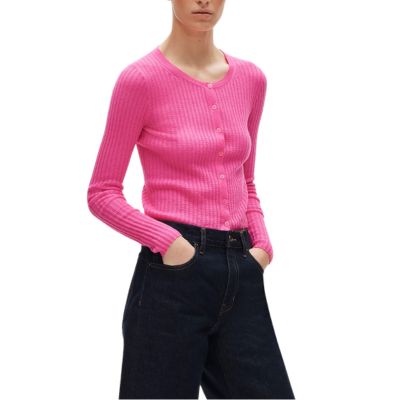 A woman wearing a pink button-front cardigan and black pants