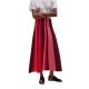 A woman wearing a white top, black sandals, and skirt with vertical stripes of reds and pinks