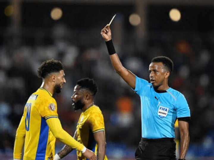 Gabon's forward #20 Denis Bouanga is shown the yellow card by Somali referee Omar Abdulkadir Artan during the Africa Cup of Nations (CAN) Group F football match between Gabon and Ivory Coast at the Grand Stadium in Marrakech on December 31, 2025. (Photo by Khaled DESOUKI / AFP via Getty Images)