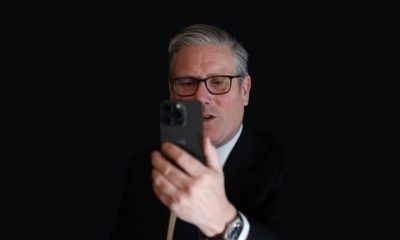 Keir Starmer looking at a phone against a dark background Social media