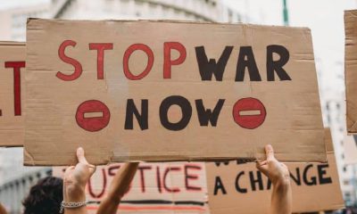 Hands holding a home made placard saying Stop War Now