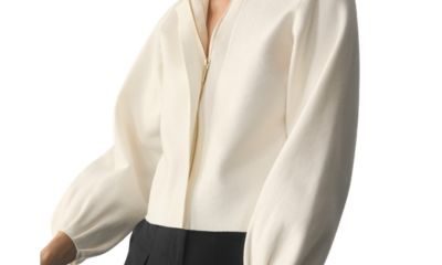 A woman wearing an ivory collarless blazer and black pants
