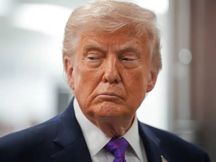 US president Donald Trump with his mouth slightly curled, looking stern with his gaze down and slightly away