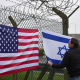 People who describe themselves as patriots display US and Israel flags as they set up their counter protest ahead of the protest by CND at RAF Fairford on March 7, 2026 in Fairford, England.