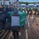 A still from a video posted on Young Bob's X account of two males pushing a large wheelie bin with a fire inside towards a row of armed riot police at far-right riots this week. Others line the pavements filming with their mobile phones and cheering the pair on