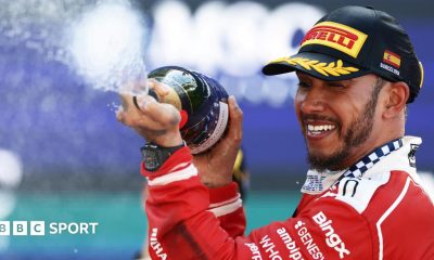 Lewis Hamilton crossing the line with Novak Djokovic waving the flag