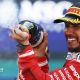 Lewis Hamilton crossing the line with Novak Djokovic waving the flag