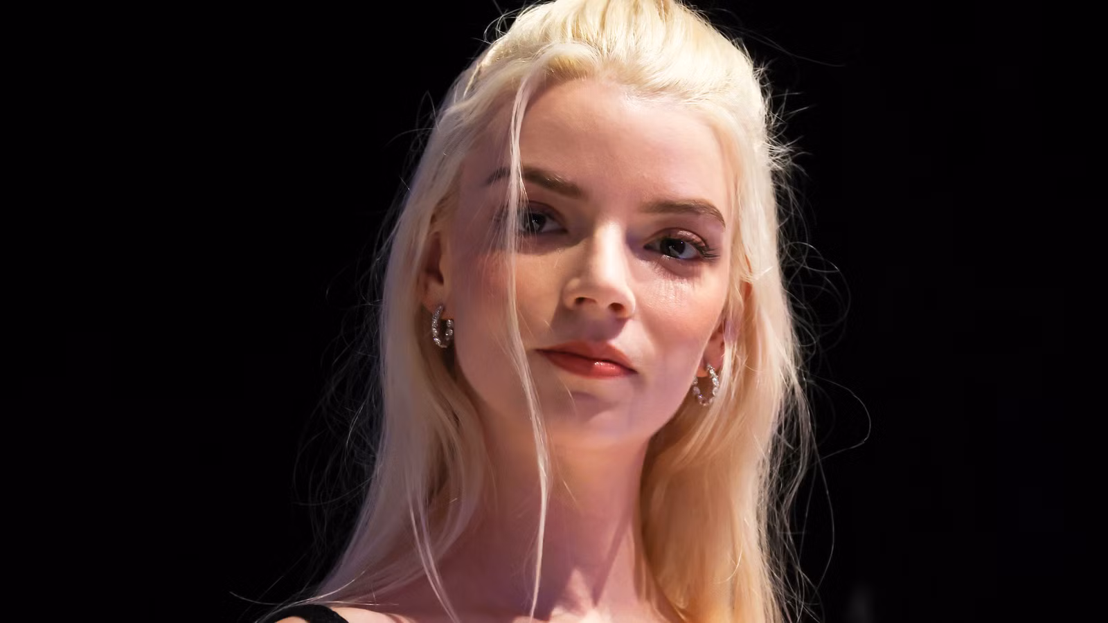 Anya Taylor-Joy smiling in front of a black background