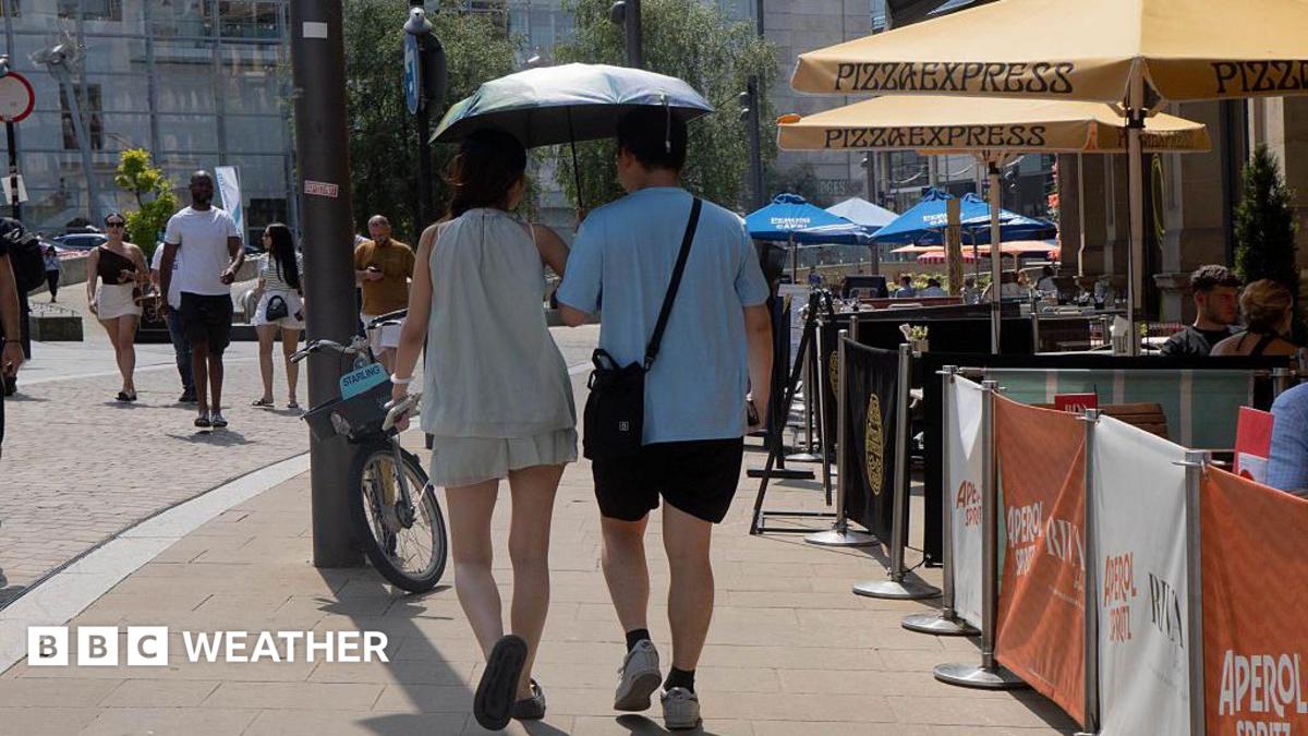 two people walking in the street holding umbrellas to shield them from the hot weather
