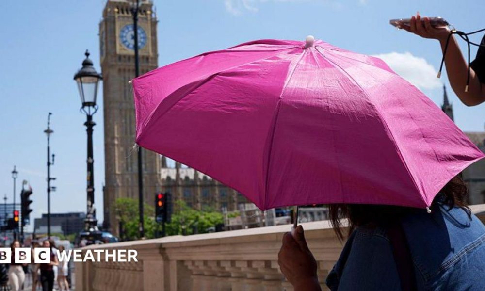 A person shielding from the Sun under an umbrella with the Houses of Parliament in the background