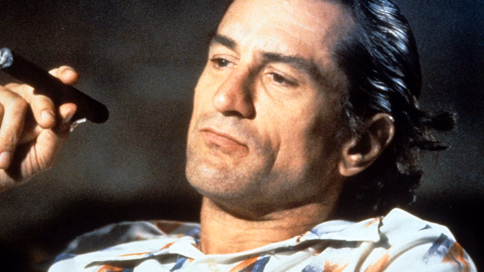 Robert De Niro as Max Caddy sitting in a theater smoking in Cape Fear