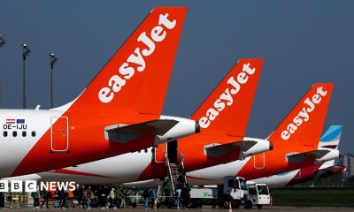The tails of three EasyJet planes, painted red and white, parked on a runway.
