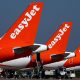 The tails of three EasyJet planes, painted red and white, parked on a runway.