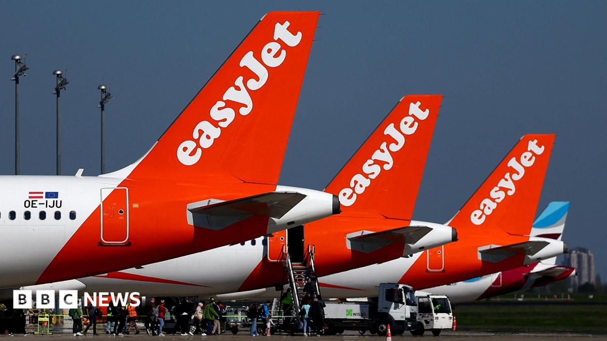 The tails of three EasyJet planes, painted red and white, parked on a runway.