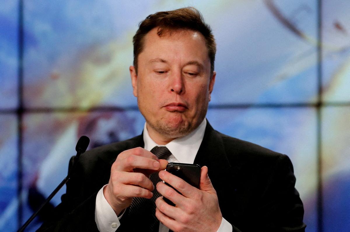Elon Musk looks at his mobile phone