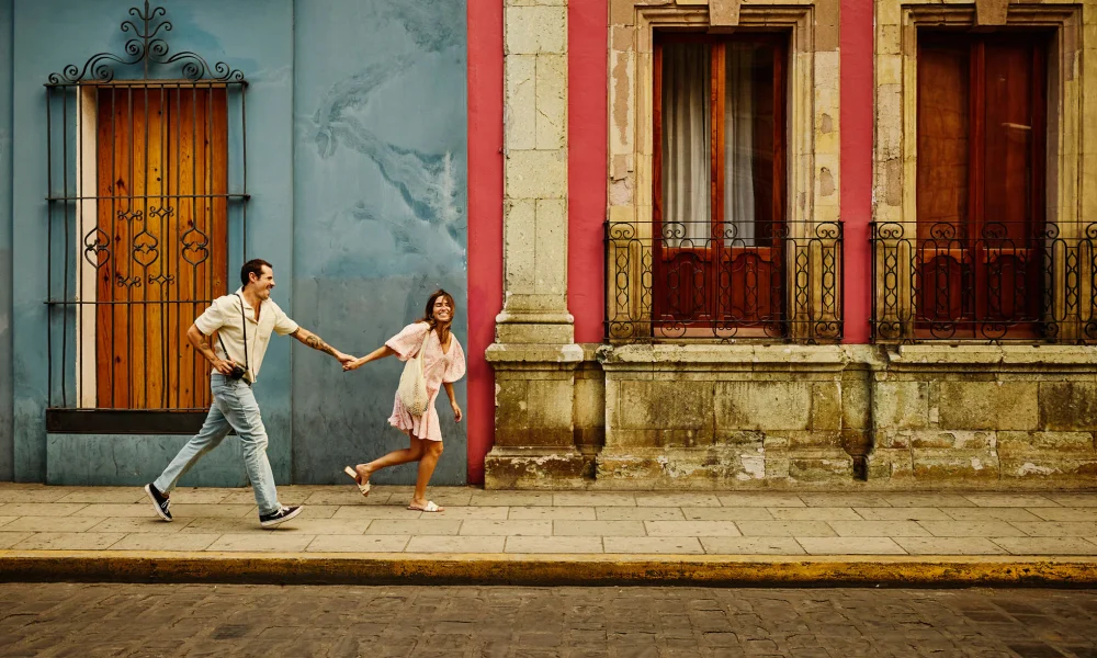 Man and woman running down a street holding hands