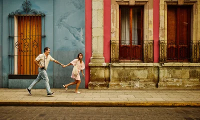 Man and woman running down a street holding hands