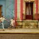 Man and woman running down a street holding hands