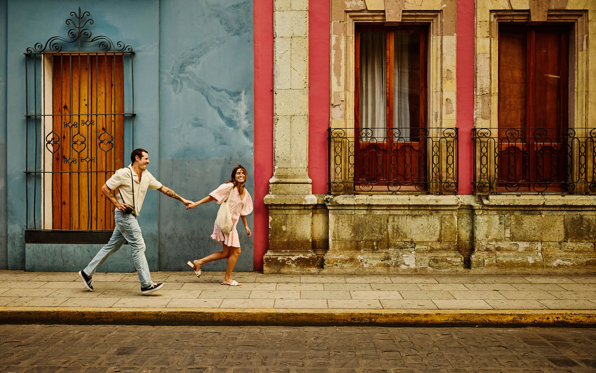Man and woman running down a street holding hands