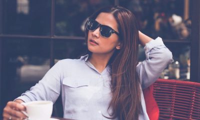 young professional woman looks hot while sitting outside; she is wearing summer work clothes of a blue button-front shirt and black pants