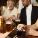 Customer paying for beers with contactless payment in pub