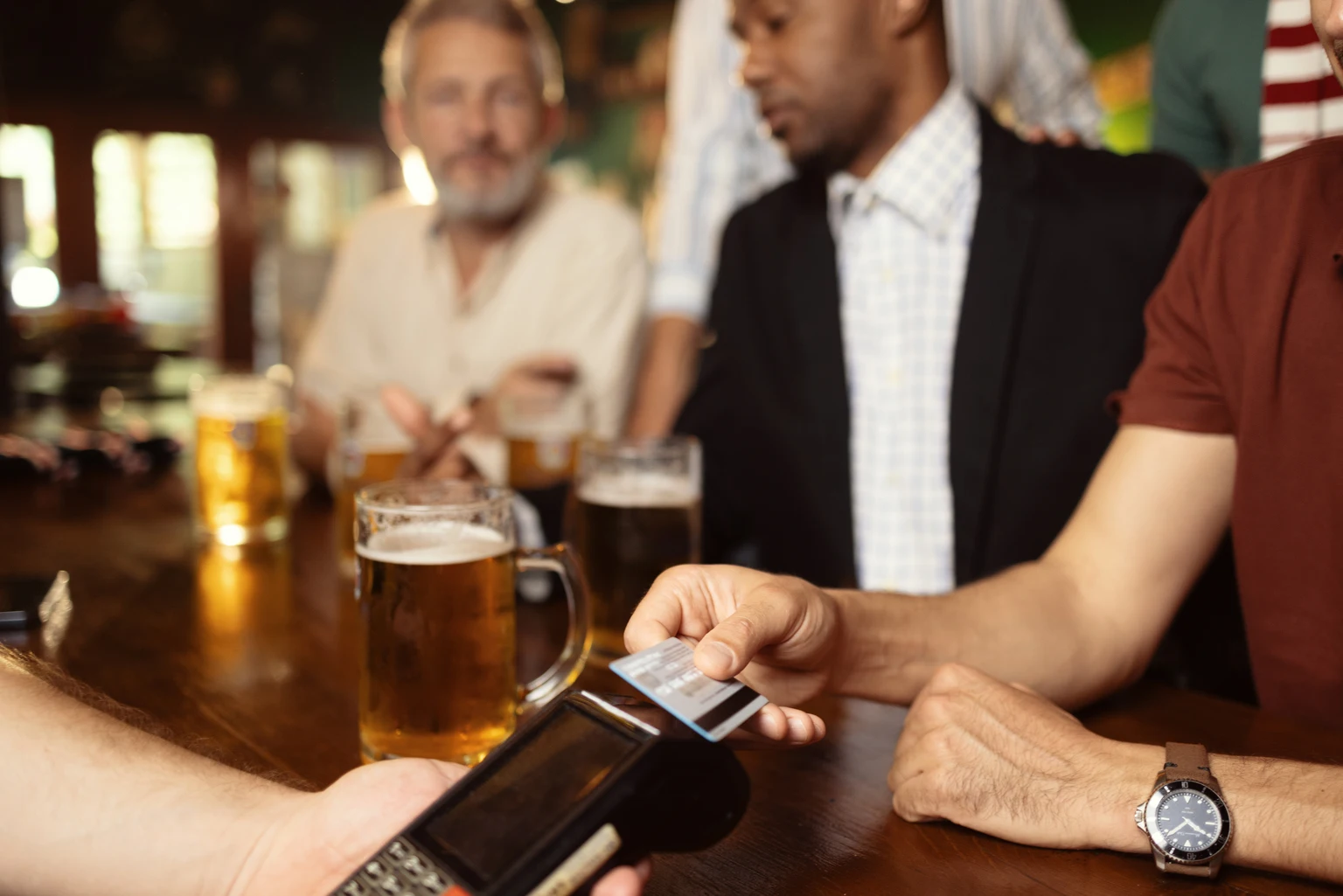 Customer paying for beers with contactless payment in pub