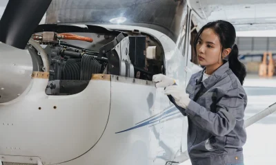 Young female mechanic works on aircraft engine inside spacious hangar during daylight hours