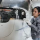 Young female mechanic works on aircraft engine inside spacious hangar during daylight hours