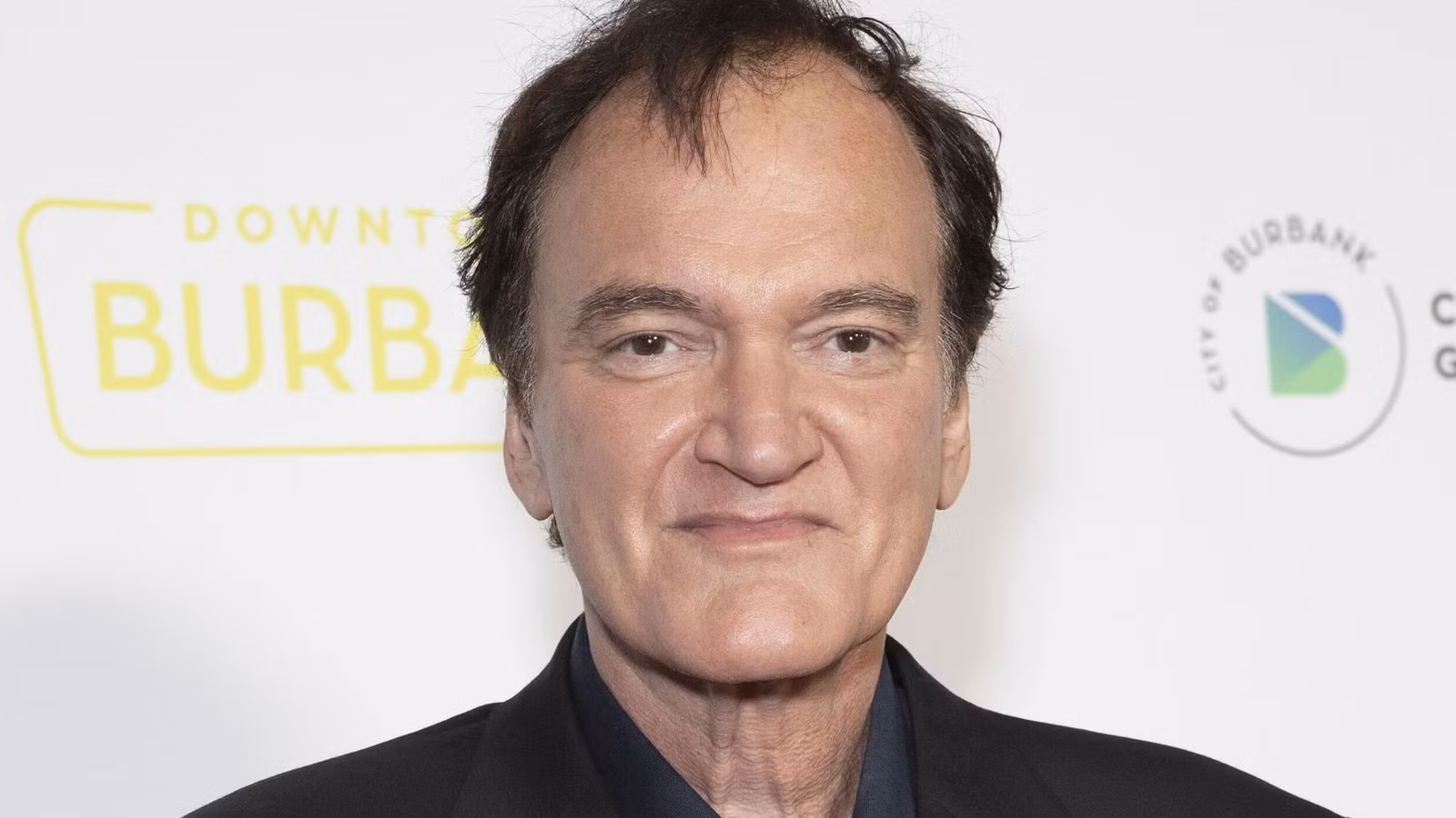 Quentin Tarantino smiling while looking at the camera.