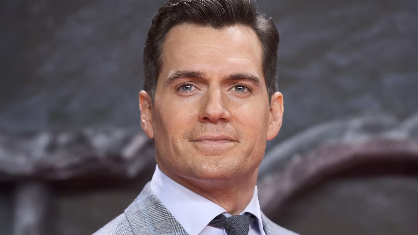 Henry Cavill wearing a suit and smiling
