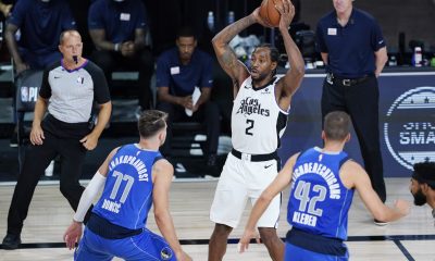 Kawhi Leonard #2 of the LA Clippers looks for help as he is defended by Luka Doncic #77 of the Dallas Mavericks and Maxi Kleber (42) during the second half of Game Three of the first round of the playoffs at the AdventHealth Arena at the ESPN Wide World O
