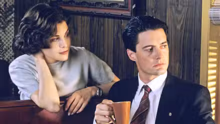 Kyle MacLachlan and Sherilyn Fenn at a booth in a diner looking out a window in Twin Peaks.