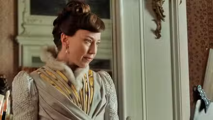 Carrie Coon looking at a portrait in progress in The Gilded Age.