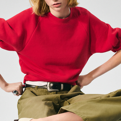 model hunches while wearing a red puff sleeve sewatshirt and olive green pants