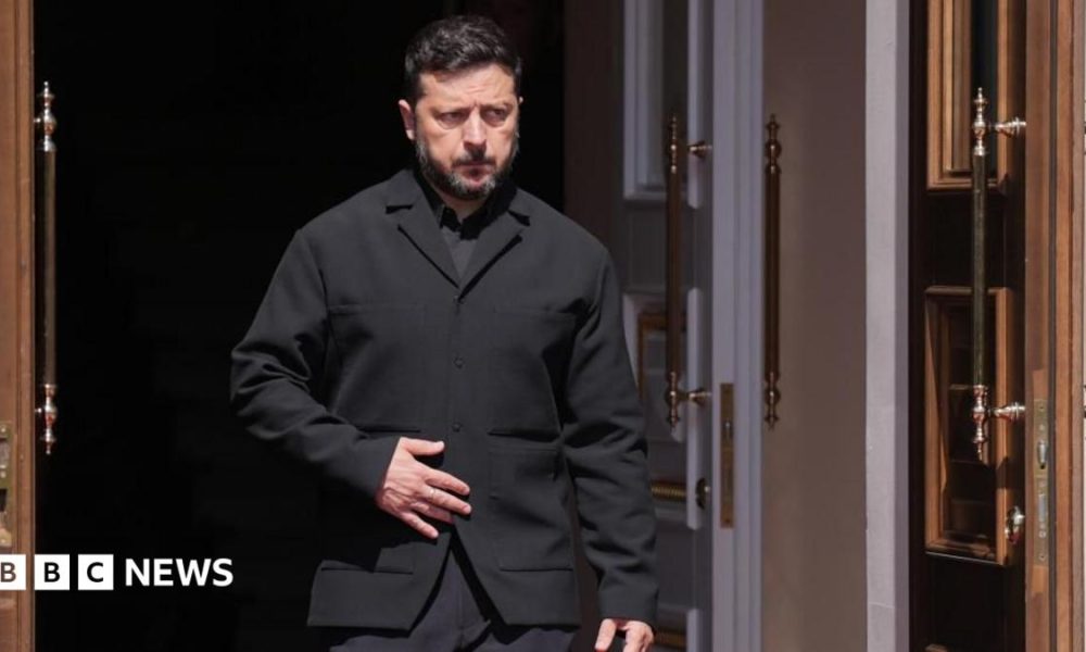 Zelensky, wearing a dark suit, walking through a doorway