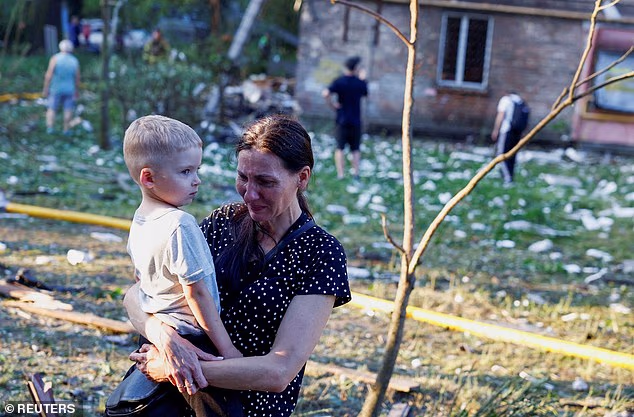 A woman cries holding a child near the site of an apartment building damaged during overnight Russian missile and drone strikes, amid Russia's attack on Ukraine, in Kyiv, Ukraine, July 2
