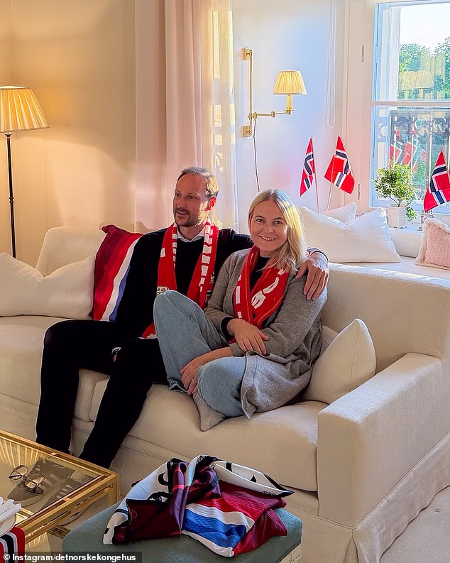 The princess, 52, was dressed casually in a grey coat, red football scarf, jeans, and thick socks, and wore no makeup in images of her watching Norway defeat Brazil 2-1 on TV with Crown Prince Haakon at their official residence in Oslo