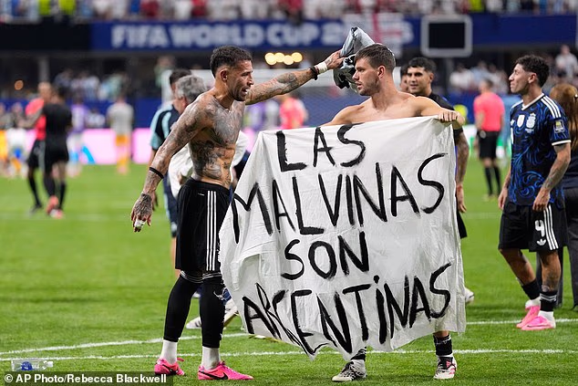 Lisandro Martinez and Giovani Lo Celso celebrated on the pitch with the sign after the final whistle blew - before they were joined by their fellow teammates