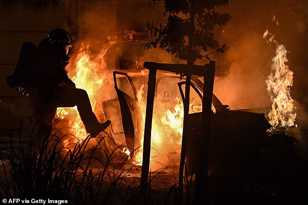 A firefighter sprays water on burning cars during a fire in front of a camping site in Villeneuve-les-Beziers, Southern France