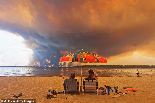 Beach goers sit on the beach of Moutchic in Lacanau, southwestern France on July 24