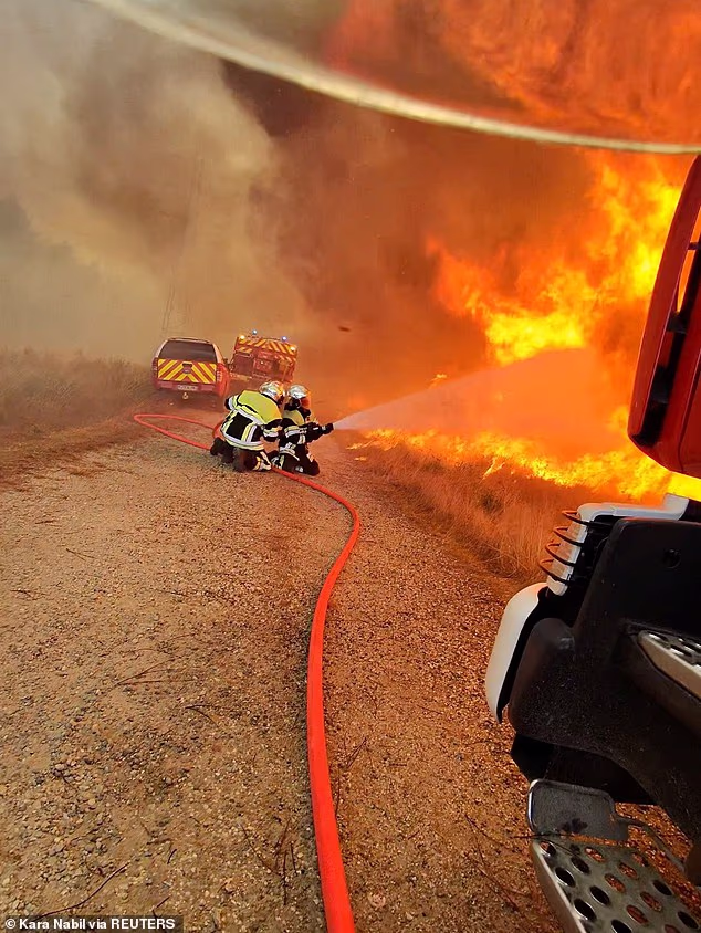 Firefighters work as flames and smoke rise during a wildfire, amid drought conditions following a heatwave and water shortages across much of France