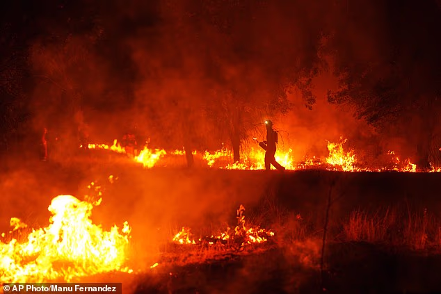 Firefighters use controlled burning to halt a wildfire that continues to spread near Cebreros, Spain, on July 28, 2026