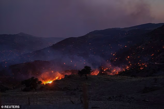 Flames and ember rise as a wildfire burns next to the village of Krya Vrysi on the island of Crete