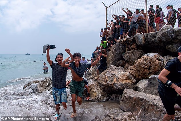 Young migrants celebrate as they arrive onto the shores of Ceuta in Spain