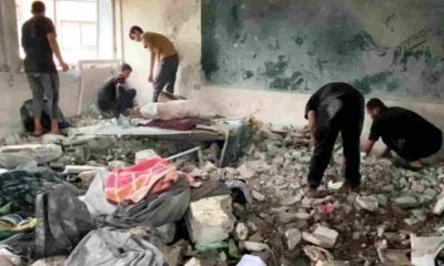 A destroyed classroom in Gaza with men tending to the concrete rubble on the floor