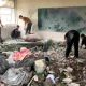 A destroyed classroom in Gaza with men tending to the concrete rubble on the floor