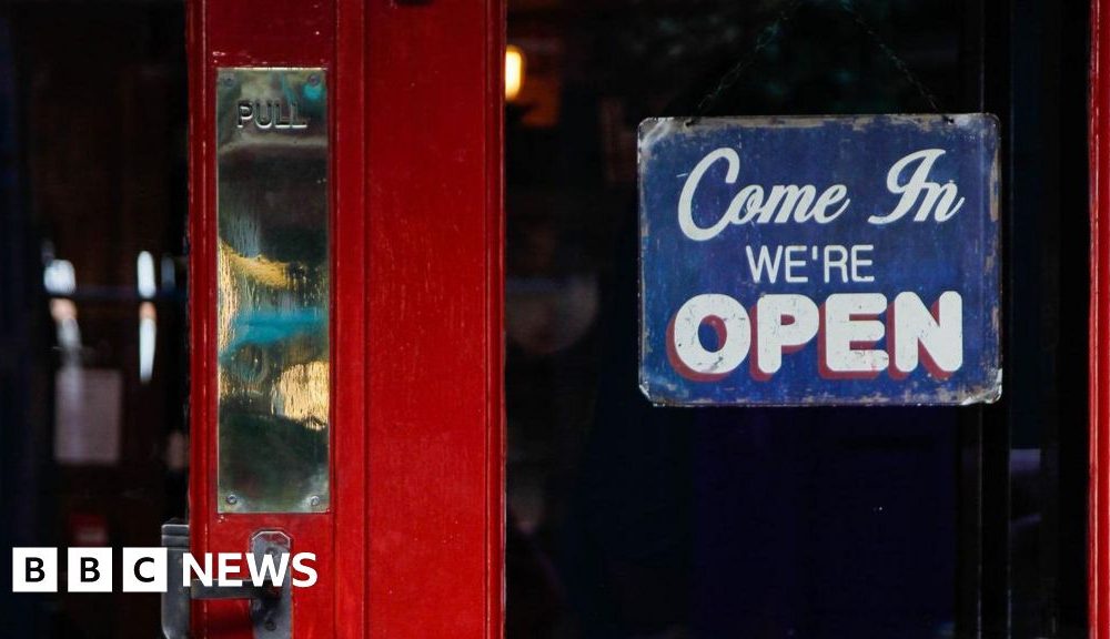 A red pub door with a 'Come in we're open' sign