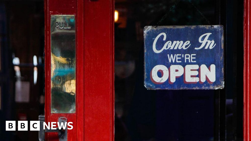 A red pub door with a 'Come in we're open' sign