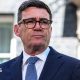 Prime Minister Andy Burnham wears dark-rimmed glasses and a blue suit.