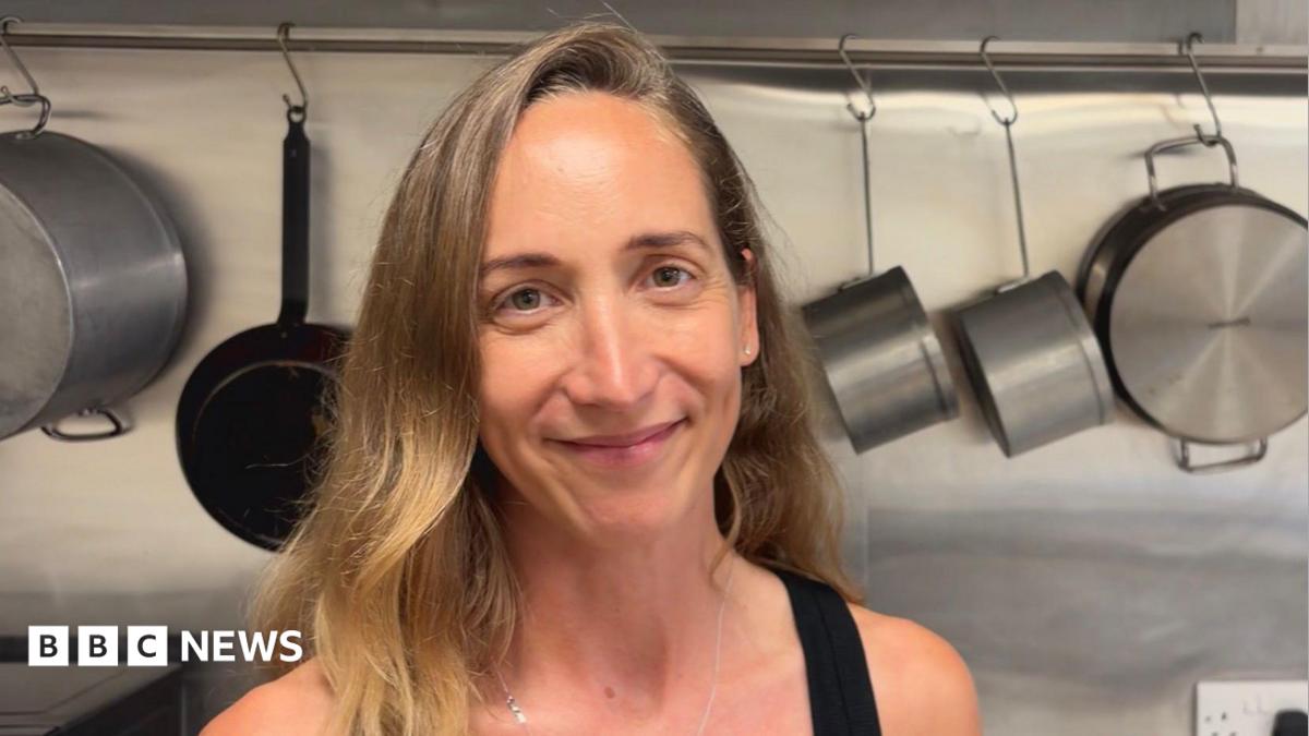 Lady stood in a kitchen in front of pots and pans.